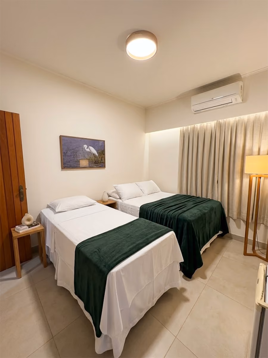 Quarto de Hotel com duas camas bem arrumadas.